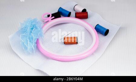 Cross stitch embroidery materials with needle, floss, thread, scissors on a white background. Stock Photo
