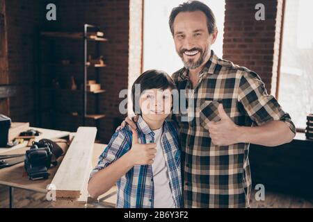 Portrait of two nice person cheerful woodworkers handymen generation showing thumbup well done at course class studio modern loft industrial brick Stock Photo