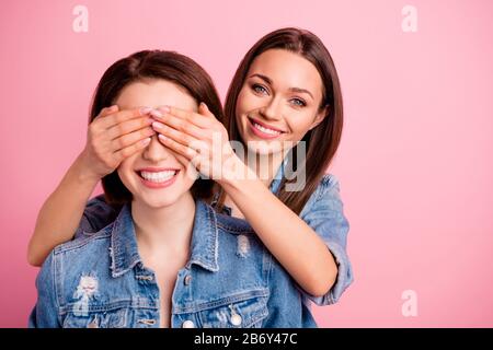 Close up photo two beautiful she her sisters ladies hide eyes hands arms try guess who unexpected meeting best buddies glad see fellows wear jeans Stock Photo