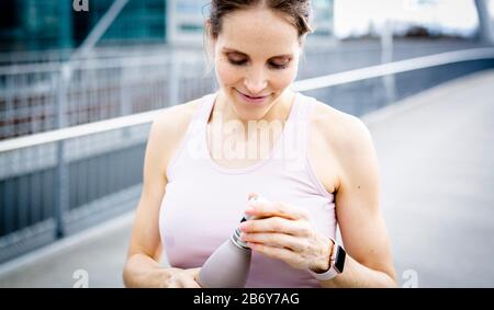 Junge athletische Frau nach dem Joggen mit Wasserflasche in der Hand.Young athletic woman after jogging with water bottle in hand.