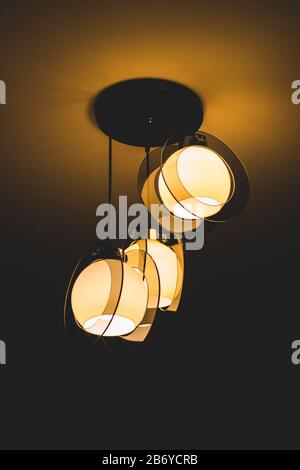 Chandelier slightly illuminating the ceiling of a room Stock Photo