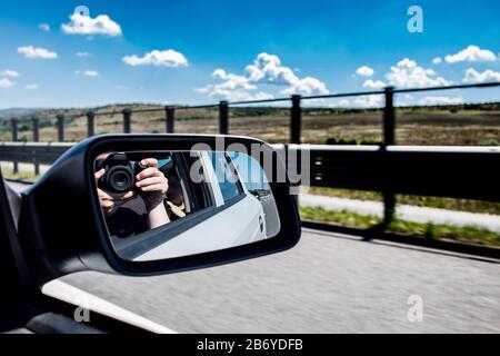 Mirror reflection of a man taking a photo with a camera in a car Stock Photo