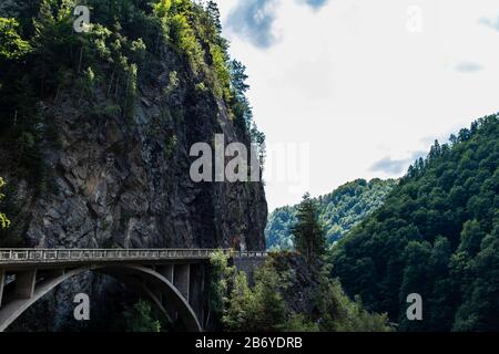 Mountain road passing through forest covered rocky mountain and large forest on Transfagarasan Stock Photo