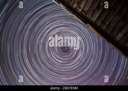 Star trails near the north star above the roof of the house in the summer Stock Photo