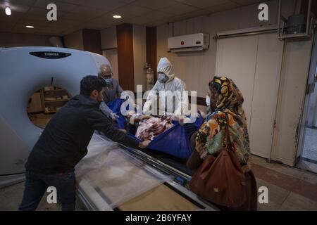 Tehran, Iran. 12th Mar, 2020. An Iranian medical personnel wearing protective gear helps the family of a patient to carry her on a CT Scan of the Rassolakram hospital in western Tehran following a new coronavirus (Covid-19) outbreak in Iran March 11, 2020. Photo by Morteza Nikoubazl/UPI Credit: UPI/Alamy Live News Stock Photo