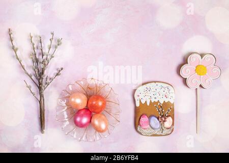 Easter festive background. Row of  Easter decorations: color eggs in glass plate, Easter gingerbreads, willow twigs and bokeh overlay on pink backdrop Stock Photo