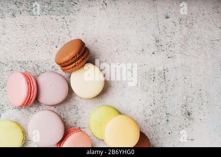 Multicolored macaroni cookies lie on a gray stone slab. Still-life of confectionery products. Stock Photo
