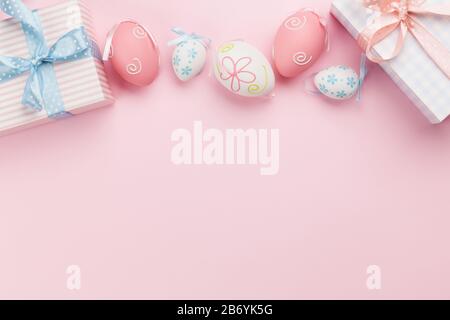 Easter greeting card with gift boxes and colorful easter eggs on pink background. Top view flat lay with space for your greetings Stock Photo