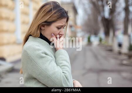 Depressed sad woman in profile almost crying on a city street in Europe, looking down, crying because of her boyfriend betrayal