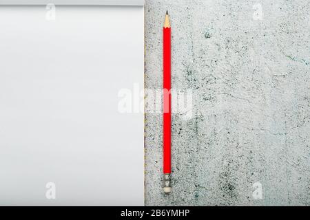 Notepad with a red pencil on a light background for writing. Free empty space for writing on a blank sheet of a notebook, concept. Stock Photo