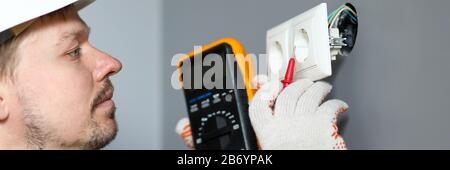 Electrician in helmet measures level electricity Stock Photo