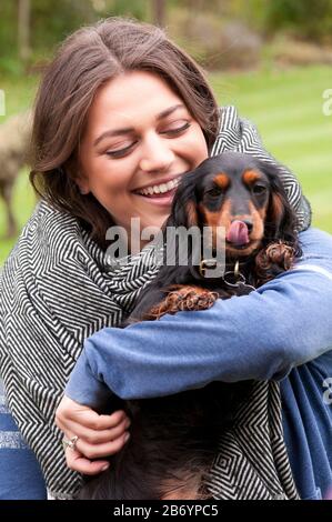 Happy young woman cuddling her miniature long haired dachshund Stock Photo