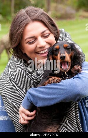 Happy young woman cuddling her miniature long haired dachshund Stock Photo