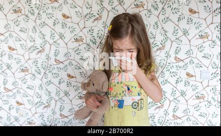 The child is allergic to pollen and allergic to animals, so he sneezes in a handkerchief. The child has a cold, sneezes and coughs. Symptoms of the co Stock Photo