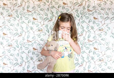 Symptoms of influenza and colds in a child. The girl became infected and sneezes. Allergic runny nose in a child during the flowering season of plants Stock Photo