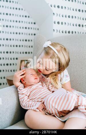 Closeup portrait of two sisters sitting together in a rocking chair Stock Photo