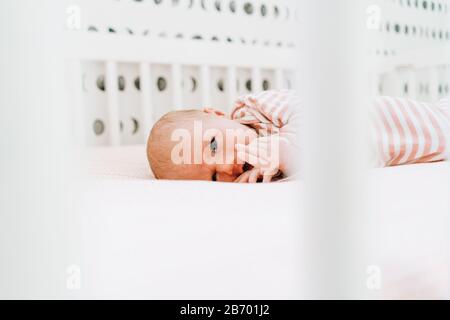 View through a crib of a newborn girl looking at the camera Stock Photo
