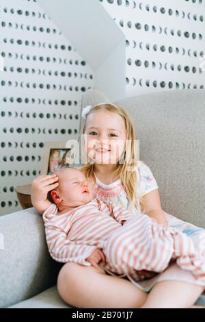 Straight on portrait of a young girl holding her baby sister Stock Photo