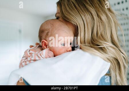 Closeup portrait of a newborn baby girl being held by her mother