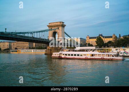 sunset cruise boat by SzÃ©chenyi Chain Bridge and four seasons hotel Stock Photo