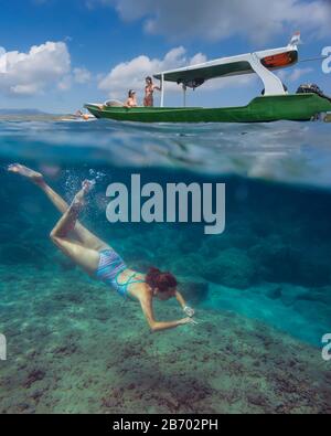 Young woman snorkeling near the boat in ocean, underwater view