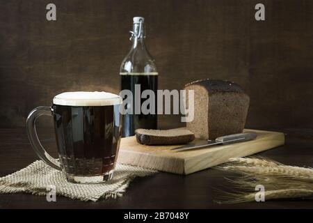 Russian beverage fermented kvass from rye bread in special half-liter mug on dark wooden background. Close up. Stock Photo