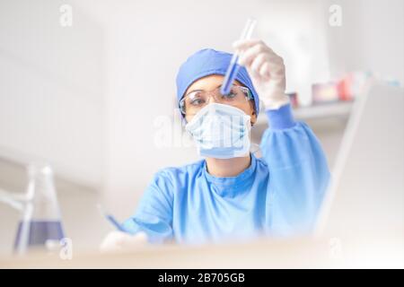 Female scientist or doctor specialist working in laboratory. Examines a substance in a test tube. Stock Photo