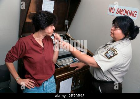 Austin Texas USA, 1997: Driving While Intoxicated (DWI) suspect takes breathalyzer test administered by sheriff's office technician. MR ©Bob Daemmrich Stock Photo