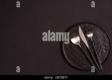 Creative tableware set from ceramic plate served fork, spoon and knife on the same color background, copy space. Flat lay. Stock Photo