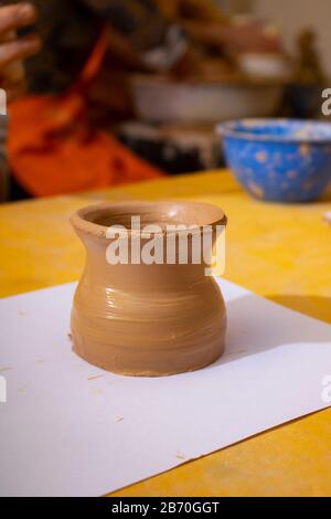 Potter make a small raw jug. Master sitting at potter wheel at work Stock Photo