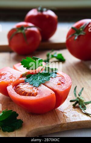 ripe tomatoes on a wooden board with parsley closeup Stock Photo
