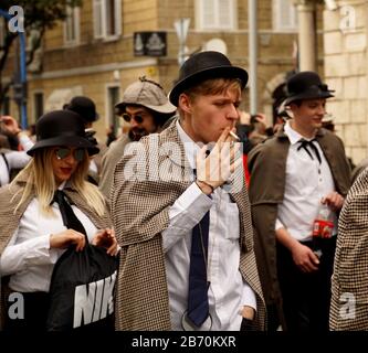 Rijeka, Croatia, February 23rd, 2020. A young boy costumed as Sherlock Holmes smokes a cigarette in a carnival procession on the town street Stock Photo
