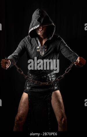 Young man posing in hooded gothic clothes looking grim. Royalty free stock photo. Stock Photo