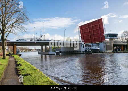 Ship on the river Rhine sails through an opened bridge called 'Dr. Albert Schweitzerbrug' in the town of Alphen aan den Rijn, Netherlands Stock Photo