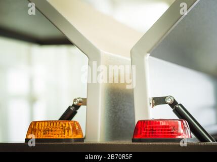 Two signal lights, orange and red, on electronics housing in front of opening housing walls with pneumatic closers Stock Photo
