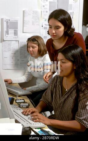 Austin Texas USA: Hispanic teen writing story for her high school newspaper as classmate looks on. MR  ©Bob Daemmrich Stock Photo