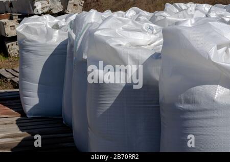 White Full big bags on wooden pallets outdoors. Storage of goods in an open storage area. Side view. Sunny spring day. Logistic topics. Selective focu Stock Photo