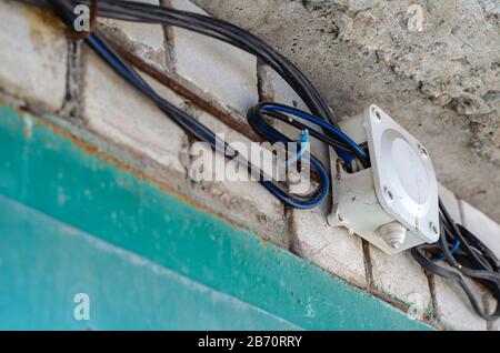 Junction box for wiring with electrical cables on the wall. Wires in black insulation are included in the plastic junction box. Wiring on a brick wall Stock Photo