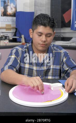 Austin Texas USA: Hispanic teen rolls a marble on a turntable to demonstrate the Coriolis effect. ©Bob Daemmrich Stock Photo