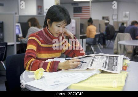 Austin Texas USA, 2002: Asian-American woman searches classified ads at state employment center.  MR   ©Bob Daemmrich Stock Photo