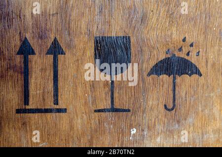 Logistic signs on the package. Three signs printed on a plywood box. Old wooden mail box. Commercial Logistic Services. Close-up. Selective focus. Stock Photo