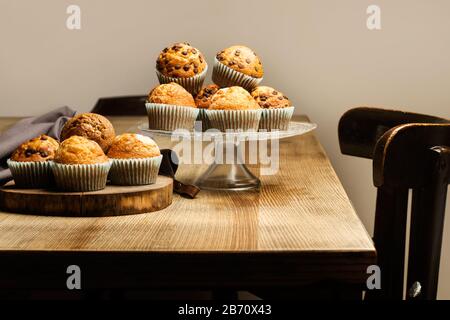 Cupcakes on a cake plate and on a tree trunk ring on a wooden table Stock Photo