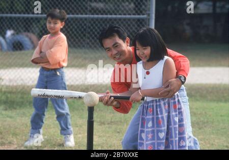 Austin, Texas USA:  Vietnamese dad shows his daughter how to bat a ball off of a tee. MR  ©Bob Daemmrich Stock Photo