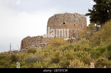 A round historic stone structure in a state of disrepair high above the city center of Hydra Port, Greece Stock Photo