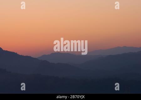 Twilight sky over hazy mountains. View from atop Mount Phou Si, in Luang Prabang, Laos. Stock Photo