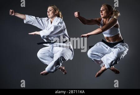 Two women athletes in training karate using sports tools. Photo of jumping girl on white background Stock Photo