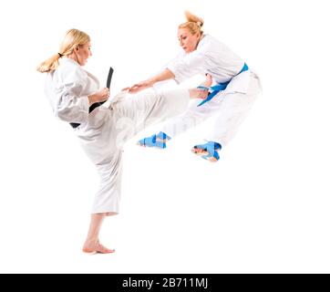 Cute blonde girls karate are engaged in training in a kimono on a white background. Young couple of athletes getting ready for a performance. Copyspac Stock Photo