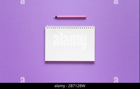 Open spiral notepad on a purple background , notebook and pen lie on textural paper, flat lay concept Stock Photo