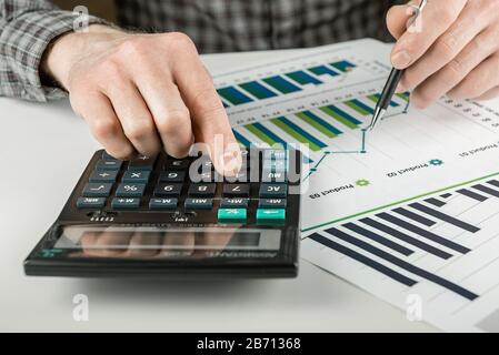 Strategy analysis concept. A man is analyzing a financial report with a calculator. Stock Photo