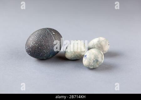 Creatively painted chicken and quail Easter eggs with natural hibiscus dye, look like sea stones on grey background. Happy Easter DIY concept. Soft se Stock Photo
